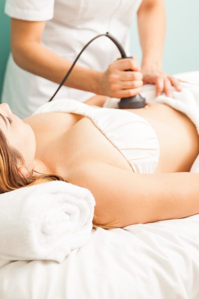 Female therapist giving a reductive and reaffirming treatment to a client and focusing on her belly