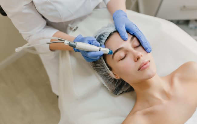 View from above rejuvenation of beautiful woman enjoying cosmetology procedures in beauty salon. Dermatology, hands in blue glows, healthcare, therapy, botox